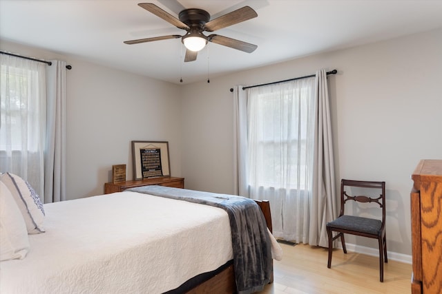 bedroom with light wood finished floors, ceiling fan, and baseboards