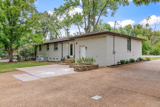 view of front of property with central air condition unit, brick siding, and crawl space