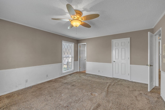 empty room featuring a textured ceiling, a ceiling fan, carpet, and ornamental molding