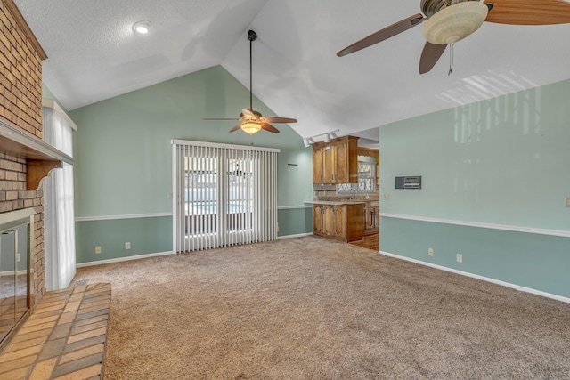 unfurnished living room with lofted ceiling, a ceiling fan, baseboards, light colored carpet, and a brick fireplace