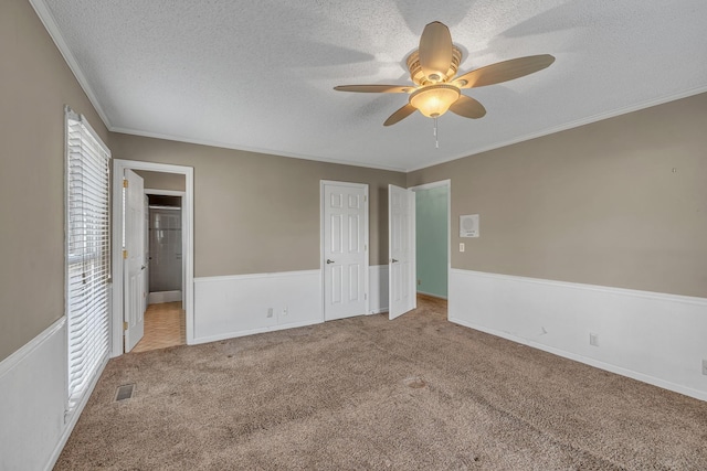 unfurnished bedroom with visible vents, a textured ceiling, carpet flooring, crown molding, and ceiling fan