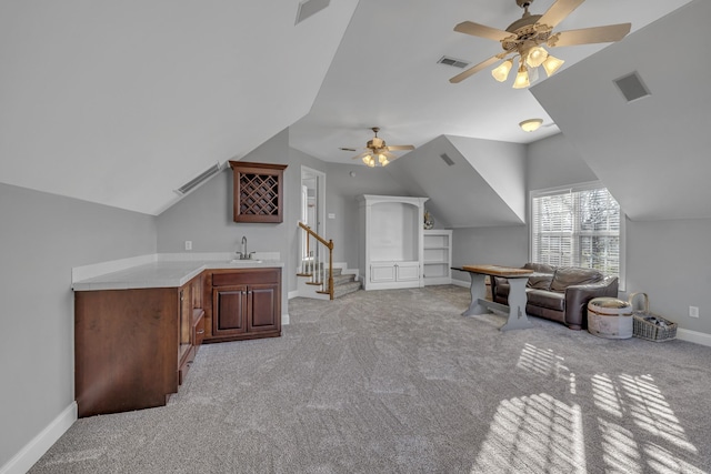 interior space featuring a sink, wet bar, baseboards, light colored carpet, and vaulted ceiling