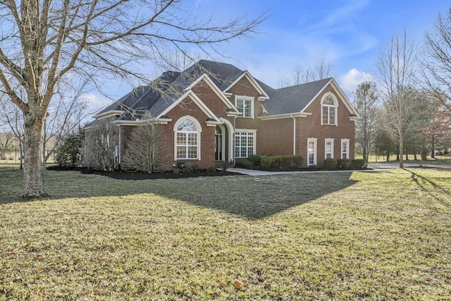 traditional-style house featuring a front lawn and brick siding