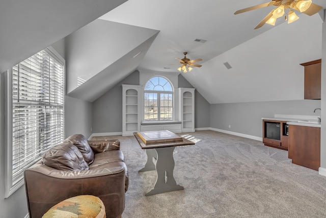 interior space with built in shelves, visible vents, baseboards, vaulted ceiling, and light carpet