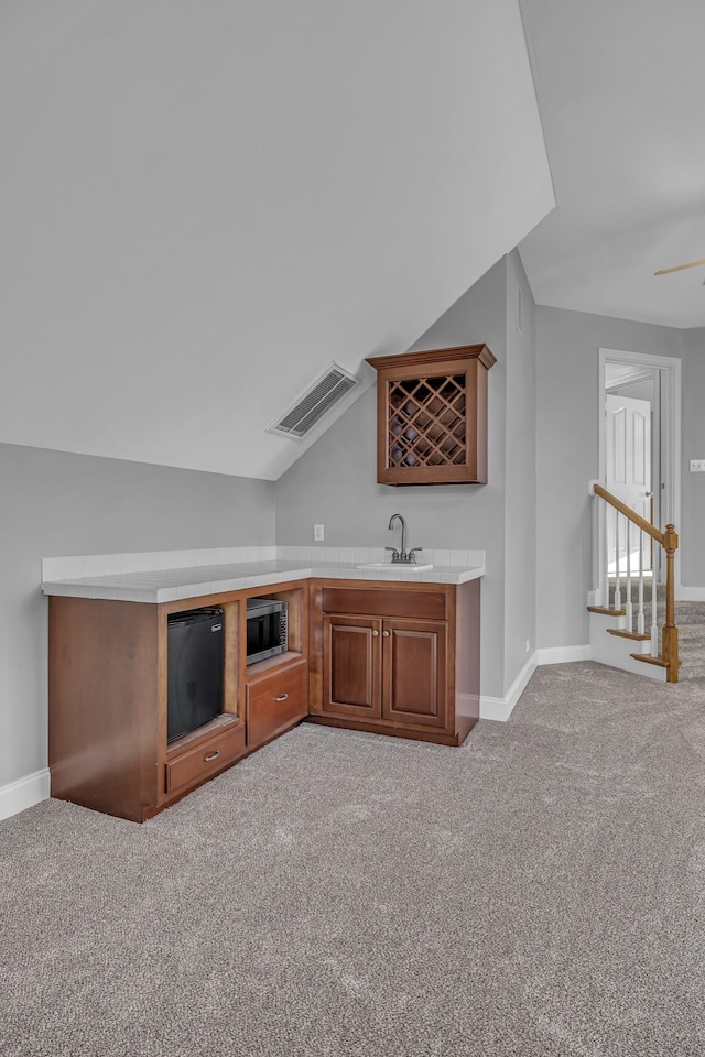 bar featuring visible vents, carpet floors, a sink, indoor wet bar, and stainless steel microwave