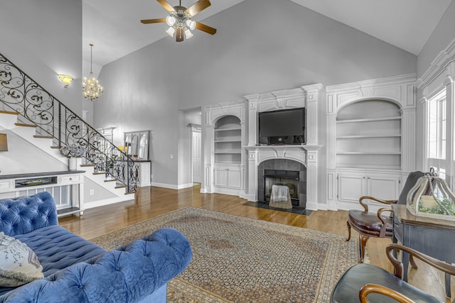 living room featuring stairway, a fireplace, built in shelves, and wood finished floors