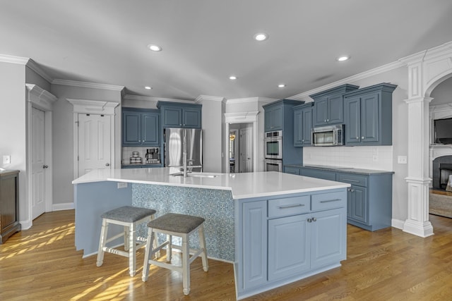 kitchen featuring blue cabinetry, a large island, light countertops, light wood-style floors, and appliances with stainless steel finishes