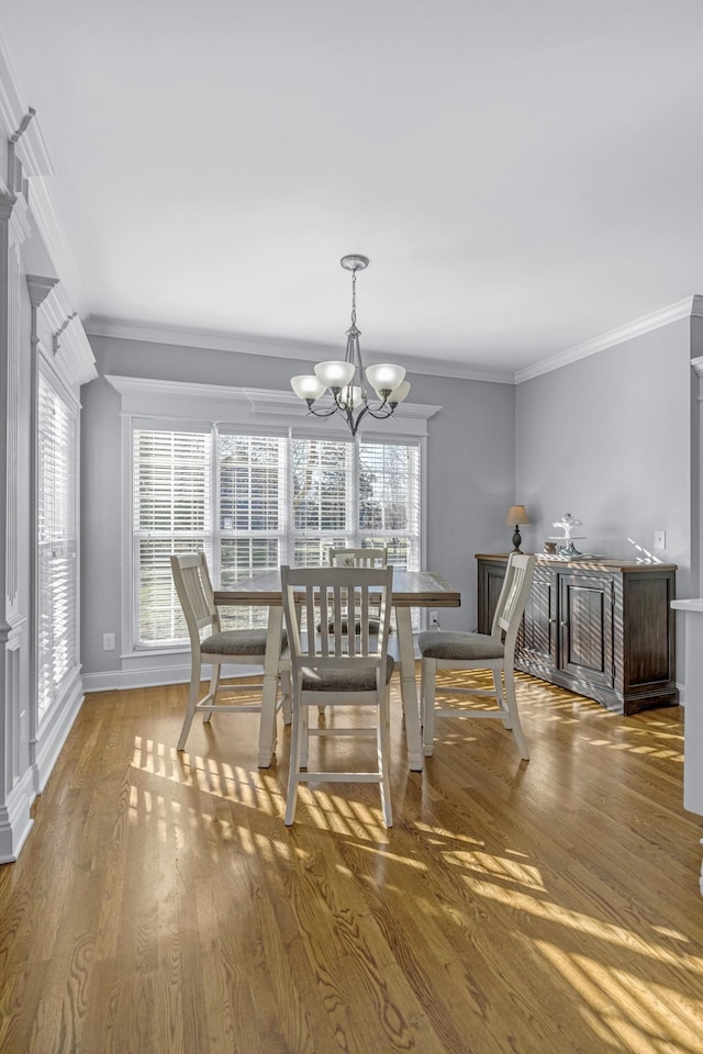 dining space featuring baseboards, a notable chandelier, wood finished floors, and crown molding