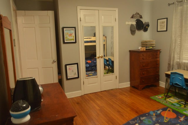 bedroom with wood finished floors, baseboards, and french doors