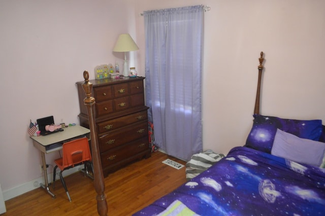 bedroom featuring visible vents, baseboards, and wood finished floors