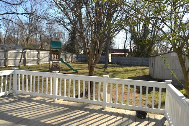 deck featuring a fenced backyard, an outdoor structure, a storage shed, a playground, and a lawn