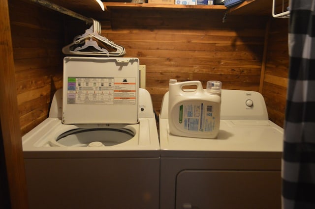 washroom featuring wooden walls, laundry area, and washing machine and clothes dryer