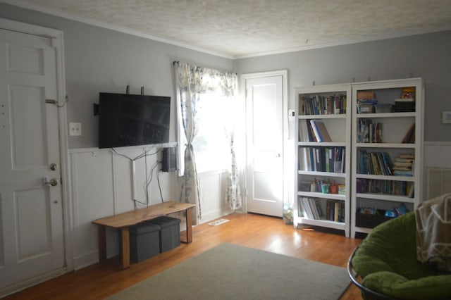 living area with crown molding, wood finished floors, and a textured ceiling