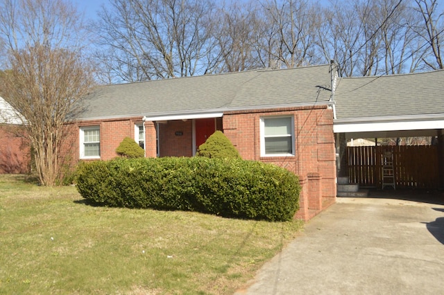 ranch-style house featuring roof with shingles, a front lawn, concrete driveway, a carport, and brick siding