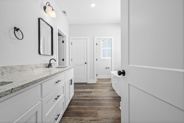 bathroom featuring visible vents, double vanity, recessed lighting, wood finished floors, and a sink