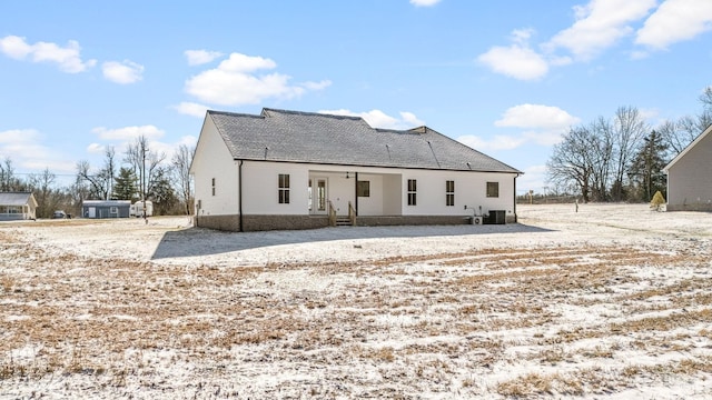 back of house featuring central AC unit and a shingled roof