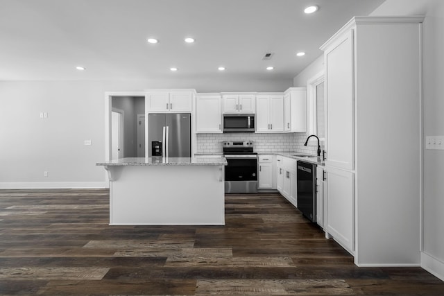 kitchen with a sink, light stone counters, backsplash, a center island, and stainless steel appliances