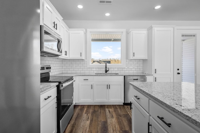 kitchen featuring backsplash, dark wood-style floors, white cabinets, stainless steel appliances, and a sink