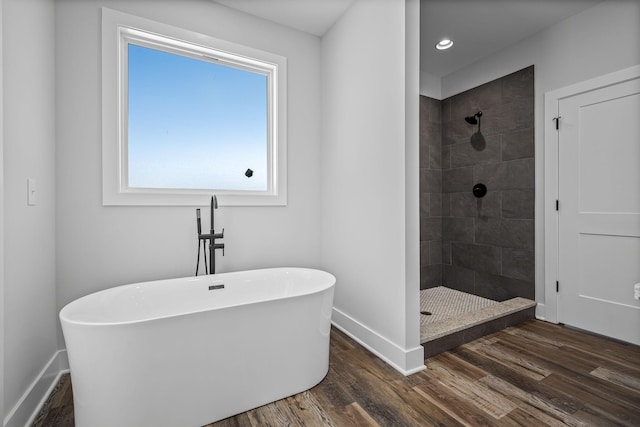 bathroom with wood finished floors, baseboards, and a tile shower