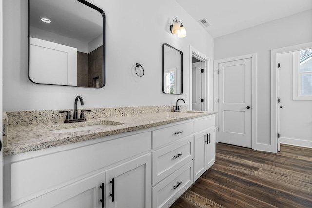 full bathroom featuring a sink, visible vents, wood finished floors, and double vanity