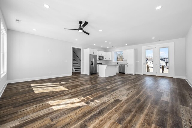 unfurnished living room with visible vents, baseboards, stairs, recessed lighting, and dark wood-style flooring