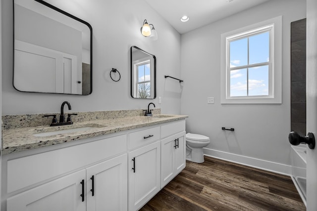 bathroom with toilet, wood finished floors, baseboards, and a sink