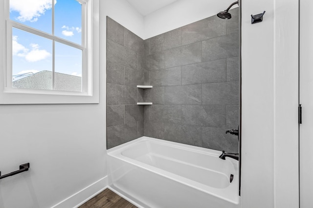 bathroom featuring baseboards, wood finished floors, and bathtub / shower combination