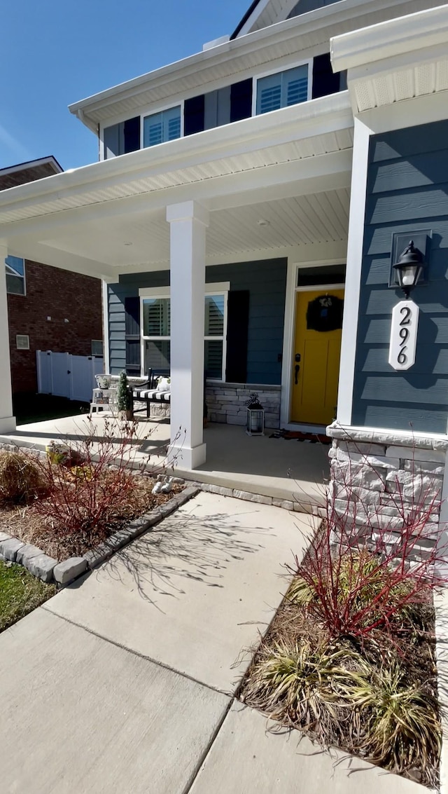 view of exterior entry featuring stone siding and a porch