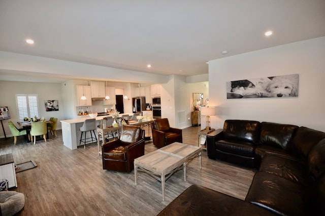 living area featuring visible vents, recessed lighting, baseboards, and wood finished floors