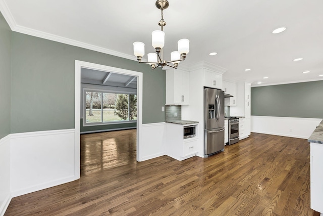 kitchen with white cabinets, appliances with stainless steel finishes, dark wood-type flooring, and ornamental molding