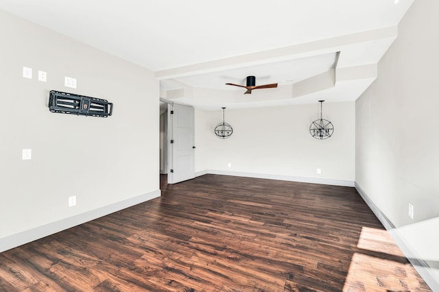 spare room with baseboards, a raised ceiling, a ceiling fan, and dark wood-style flooring