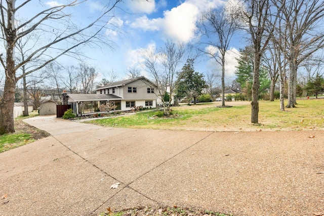 view of front of property with driveway, covered porch, a front lawn, an outdoor structure, and a storage shed