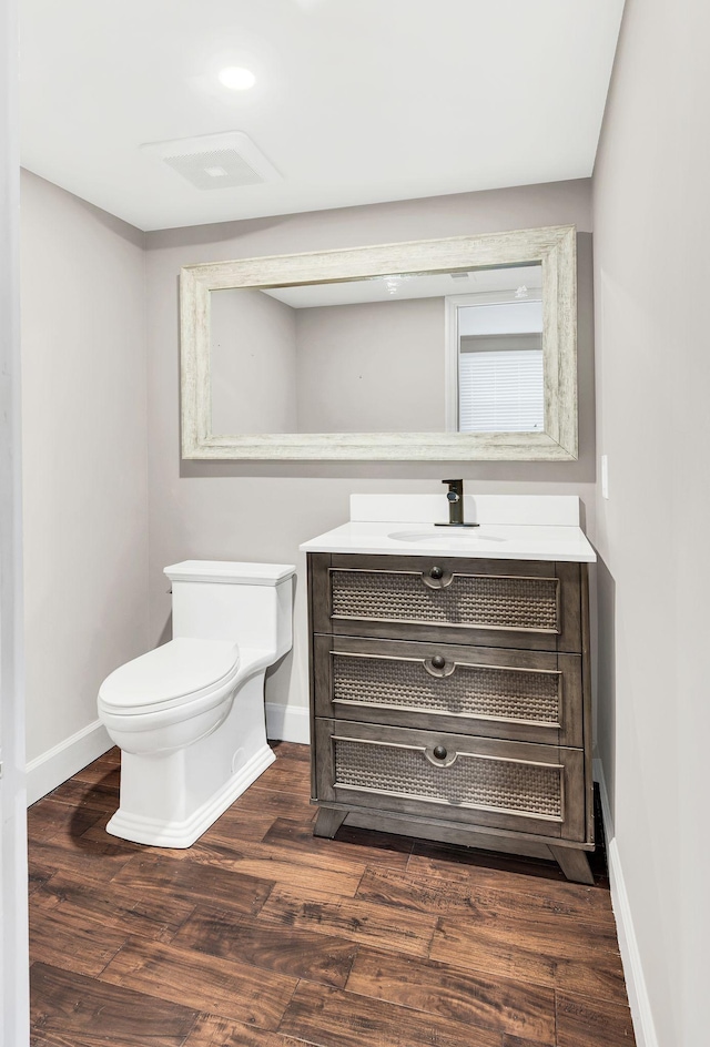 bathroom featuring baseboards, toilet, wood finished floors, and vanity