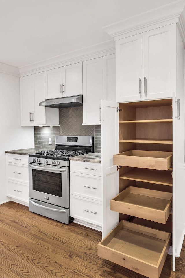 kitchen with dark wood-type flooring, under cabinet range hood, white cabinets, decorative backsplash, and gas range