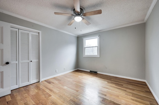 unfurnished bedroom featuring a textured ceiling, light wood-style flooring, a closet, and ornamental molding