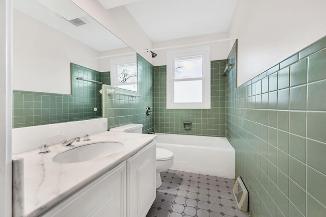 bathroom with vanity, tile walls, toilet, and tub / shower combination