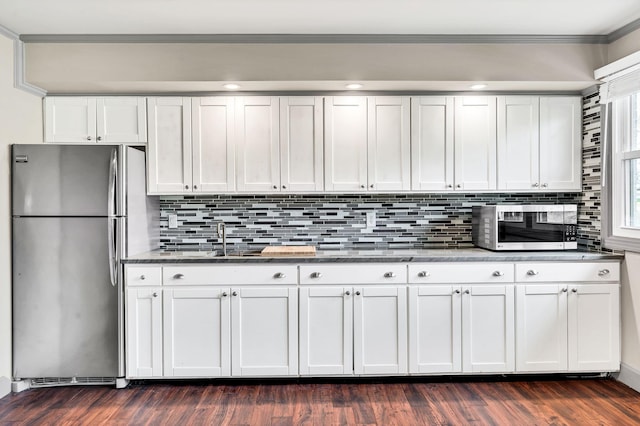 kitchen with dark wood-style floors, a sink, appliances with stainless steel finishes, crown molding, and backsplash