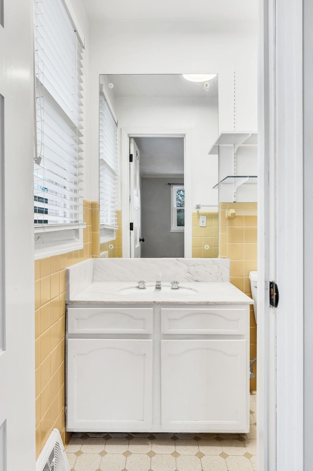 half bathroom featuring toilet, tile walls, and vanity