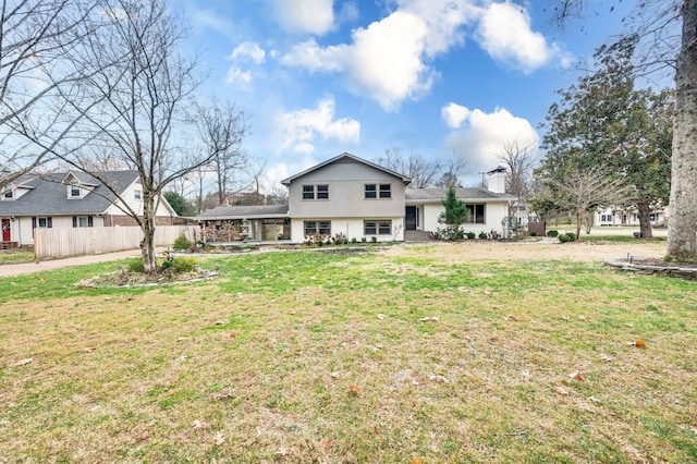 back of house with a chimney, a yard, and fence