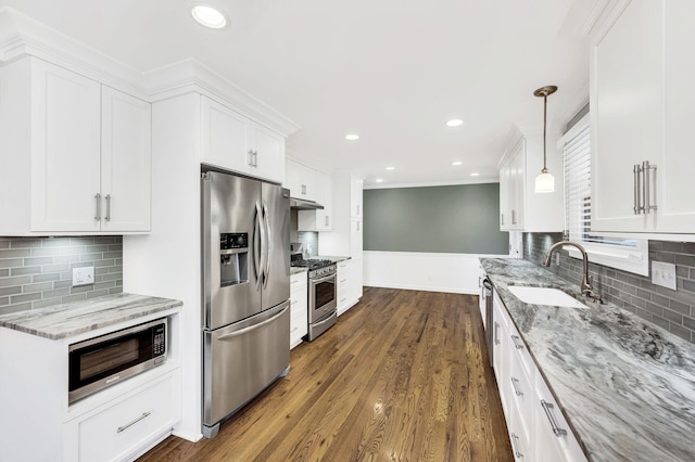 kitchen featuring light stone countertops, a sink, white cabinets, under cabinet range hood, and appliances with stainless steel finishes