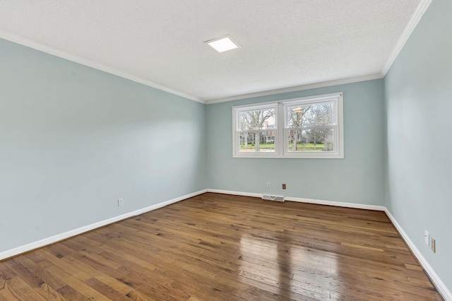 empty room with a textured ceiling, hardwood / wood-style flooring, baseboards, and ornamental molding