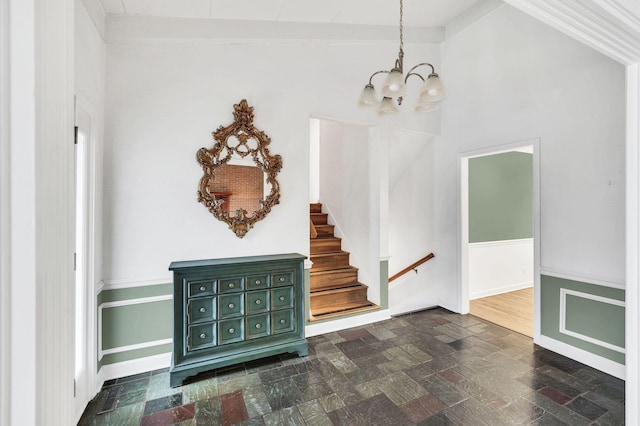 entryway with stairway, baseboards, an inviting chandelier, vaulted ceiling, and stone finish floor