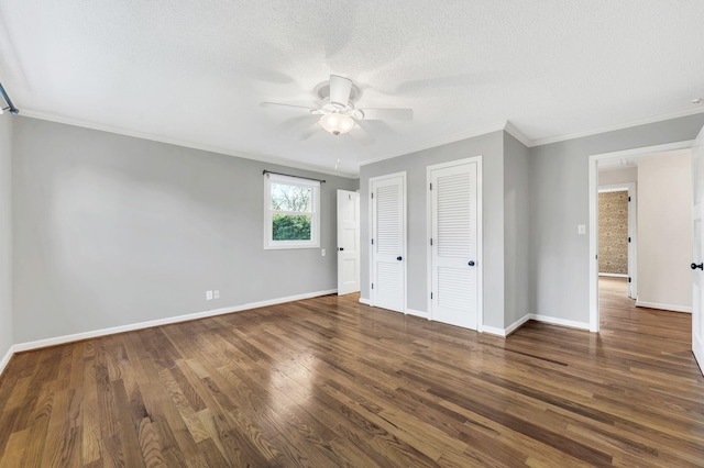 unfurnished bedroom with crown molding, baseboards, multiple closets, wood finished floors, and a textured ceiling