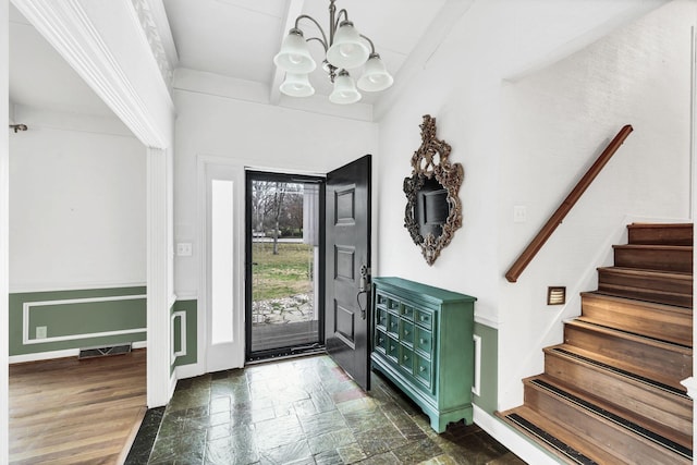 foyer with stairway, baseboards, visible vents, stone finish flooring, and a chandelier