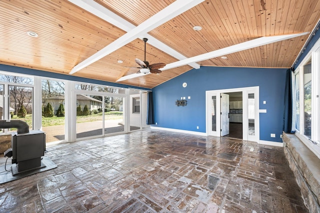 unfurnished living room featuring a ceiling fan, baseboards, lofted ceiling with beams, a wood stove, and wooden ceiling