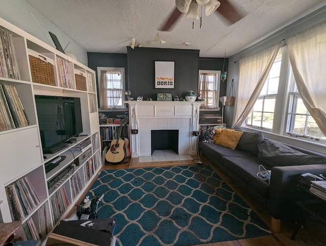 living area with plenty of natural light, a fireplace, a textured ceiling, and ceiling fan