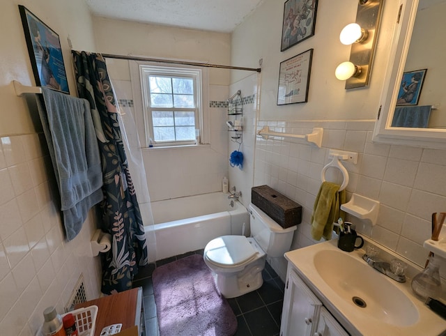 bathroom with tile patterned flooring, toilet, vanity, shower / bath combination with curtain, and tile walls