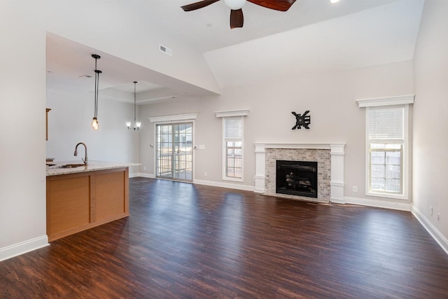 unfurnished living room with a sink, baseboards, a fireplace with flush hearth, and dark wood-type flooring