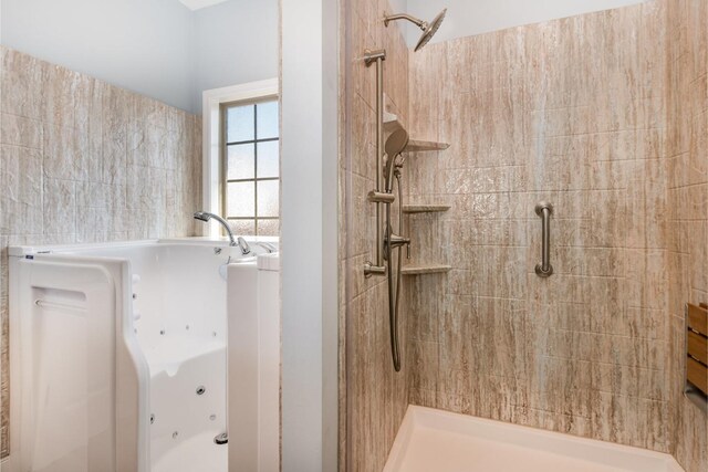 full bath featuring a jetted tub and tiled shower