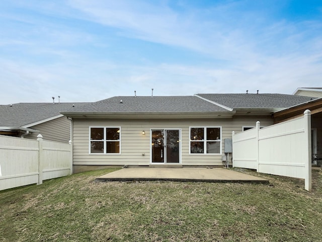 rear view of house featuring a lawn, roof with shingles, a patio, and fence